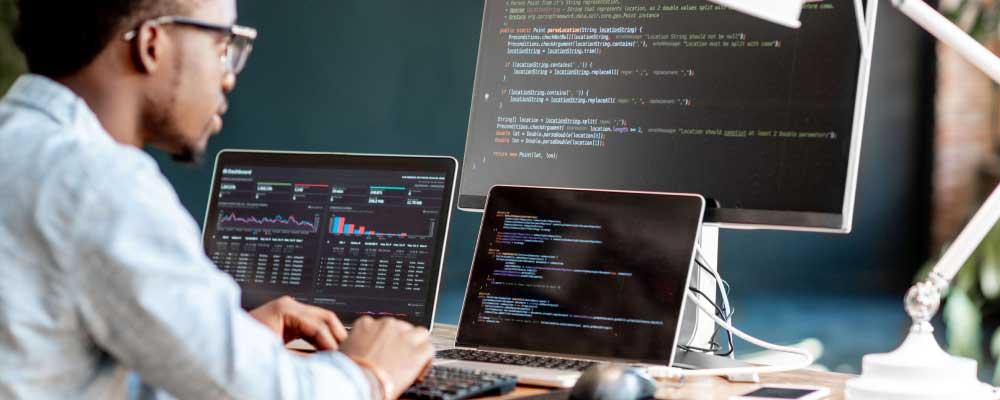 Software developer looking at computer with code on screen